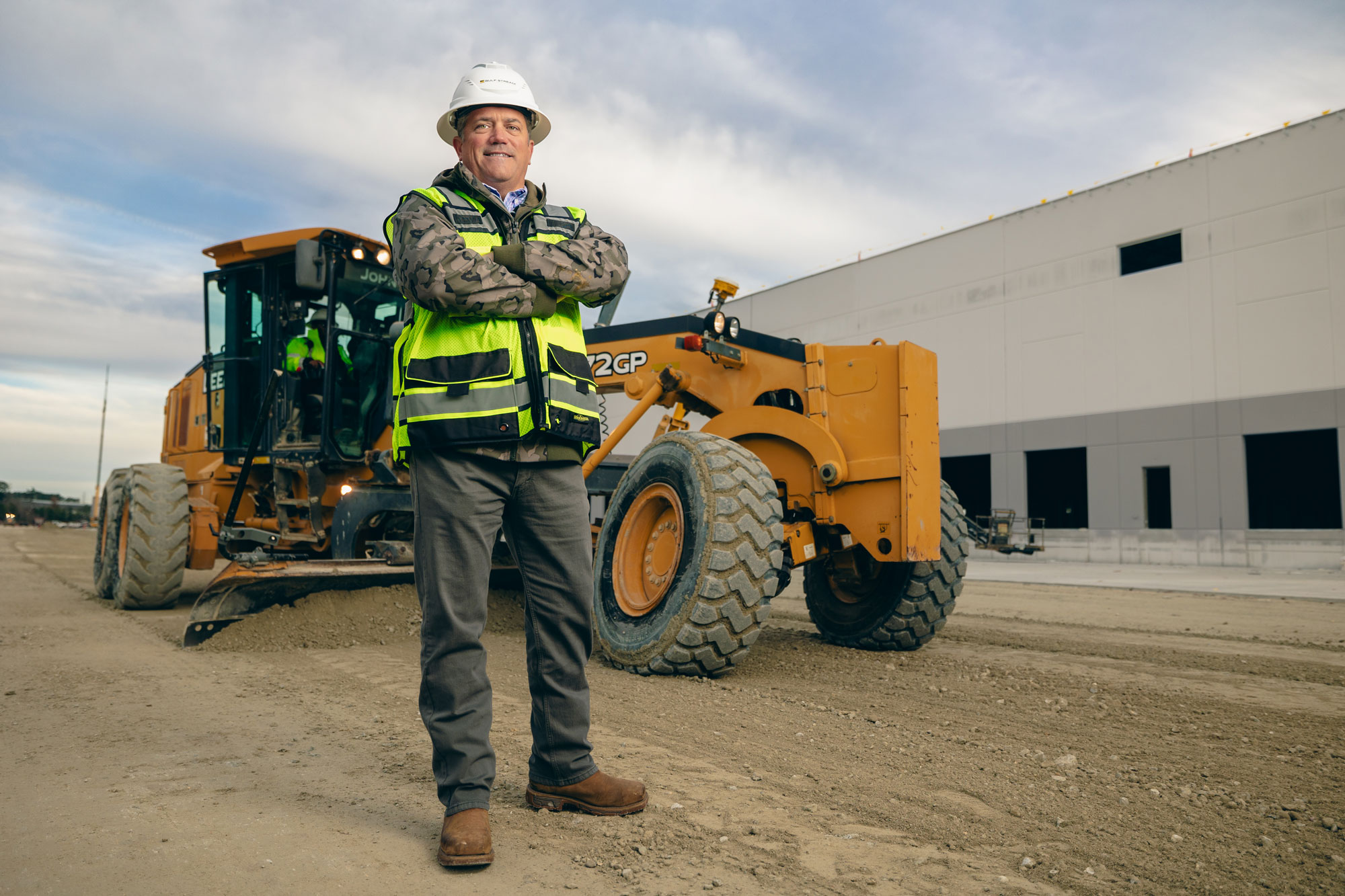 Mark Hylton standing with arms crossed in front of machinery smiling